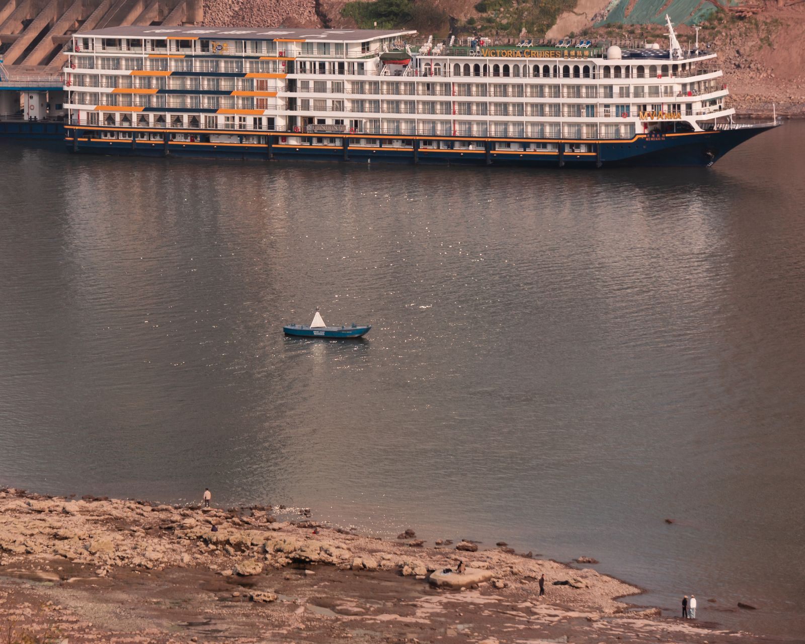 Multi-deck river cruise ship with rows of cabin windows sailing on a calm river