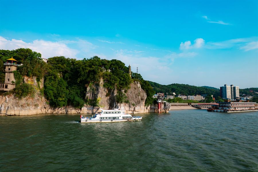 Boats on a wide Chinese river below wooded cliffs near Jiujiang